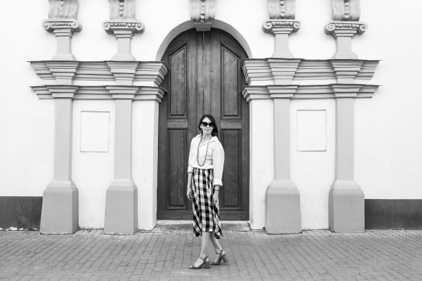 幸福的概念-快乐的女人在城市街道上玩。戴墨镜的时尚女人穿着高跟鞋走在街上。黑白图像。图片下载