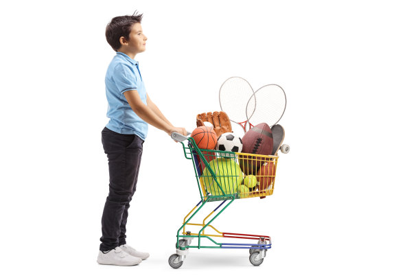 男孩站在一个小购物车里，里面装满了运动球和器材图片下载