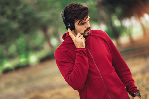 一个年轻男子的肖像在一个早晨慢跑在秋天的公园，男子听着音乐与耳机图片下载