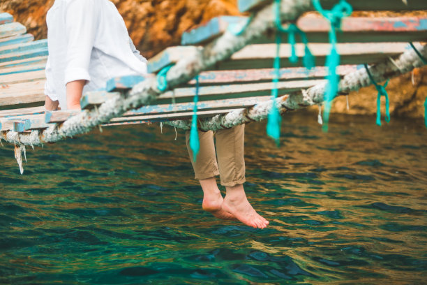 农作物图片男子坐在吊桥上把腿放在海水里夏天的时候图片下载