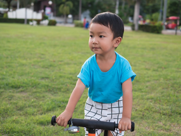 亚洲可爱的孩子男孩在蓝色t恤上的自行车与微笑的快乐的脸。图片下载