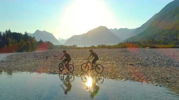 图片:美丽的风景环绕着沿着河边骑自行车的男性游客。图片下载