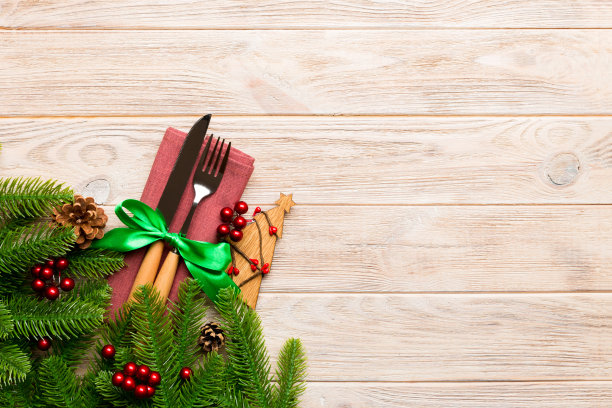 餐巾纸上的叉和刀与圣诞装饰和新年树在木制背景上的俯视图。假日和节日的概念与复制空间图片下载