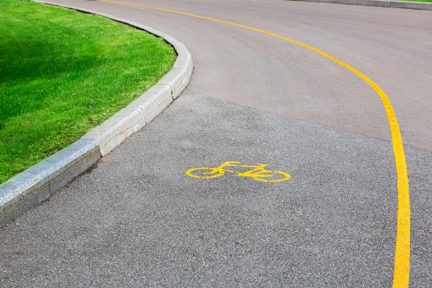 自行车标志在柏油路上，有自行车专用车道，一个空的道路与路边的绿色草地。图片下载