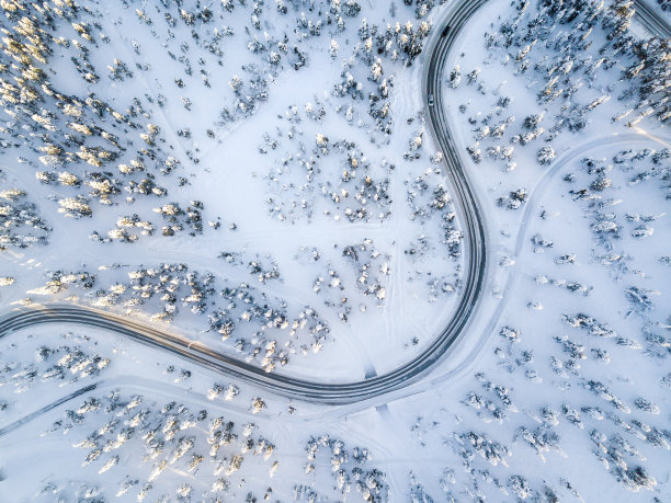 鸟瞰图冬季蜿蜒的道路在雪覆盖的森林在芬兰图片下载