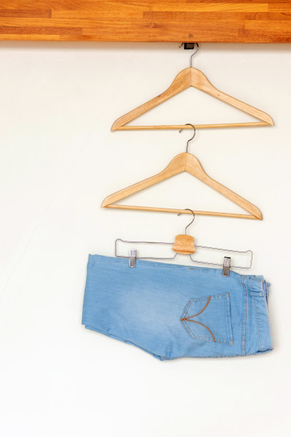 浅蓝色牛仔裤挂在小衣柜的木衣架上图片下载