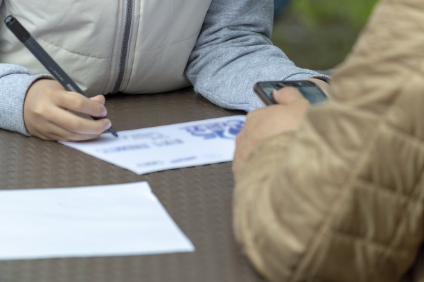 这孩子用毡尖笔在桌子上的一张纸上画画。相反，成年人手持智能手机。图片下载