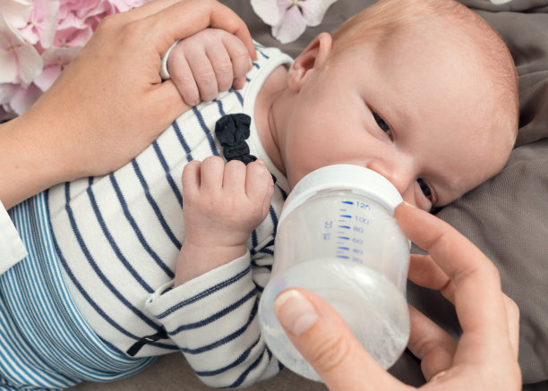 年轻的母亲在家里用奶瓶喂她刚出生的孩子素材图片