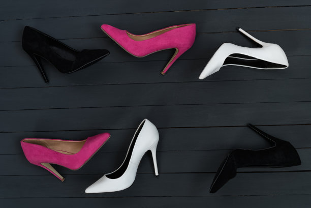 女人的高跟鞋在不同的颜色。黑色木头的背景。时尚的概念图片下载