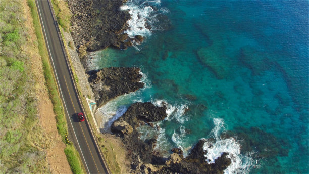 航拍:红色敞篷车在海洋悬崖上美丽的海岸公路上行驶图片下载