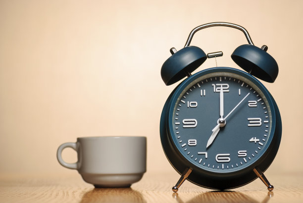 桌上放着一个闹钟和一杯咖啡图片下载