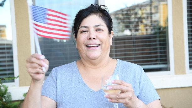 成熟的女人看着镜头摆姿势挥舞着美国国旗图片下载