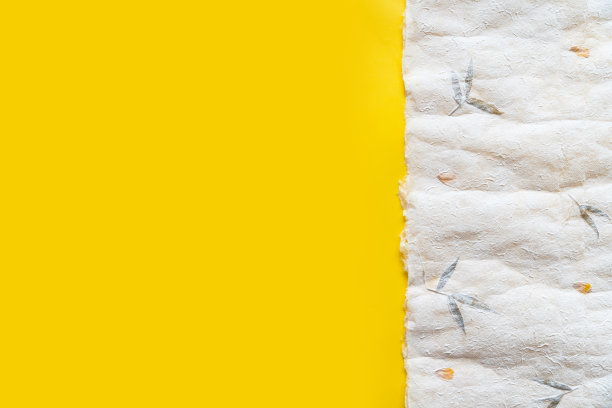 俯视图皱褶日本纸(Washi)在黄色纸三分之一的比例。纸张纹理背景与复制空间。图片下载