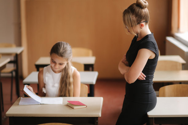 老师在课堂上帮助学生写作。教育，小学，学习和人的观念图片下载