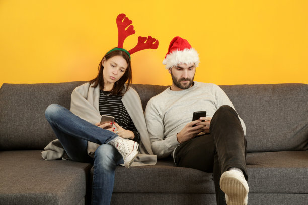 这是一对不开心的夫妇在新年前夜坐在沙发上看手机的照片图片下载
