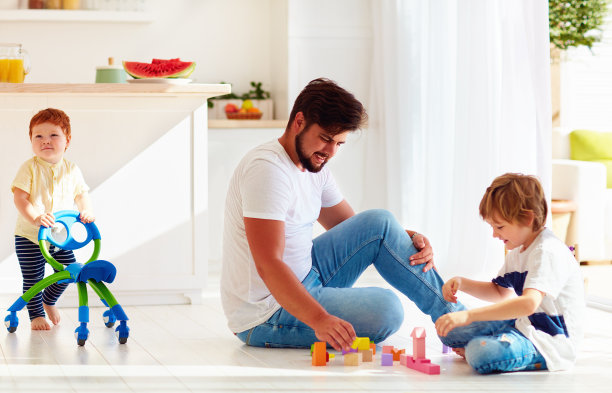 蹒跚学步的婴儿推着婴儿车走着，爸爸和孩子一起玩游戏图片下载