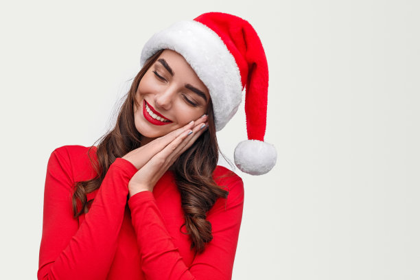 快乐的年轻女子戴着圣诞帽梦想着圣诞节图片下载