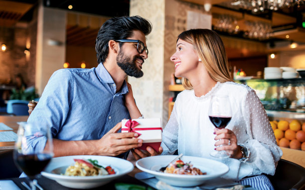 给女朋友的生日礼物。一对年轻夫妇在餐厅享用午餐。生活方式，爱情，关系，食物概念图片下载