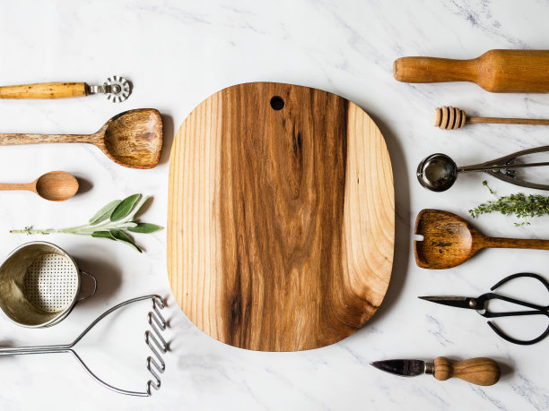 在大理石背景上平铺各种金属、木制厨房工具和生香草。前视图。图片下载