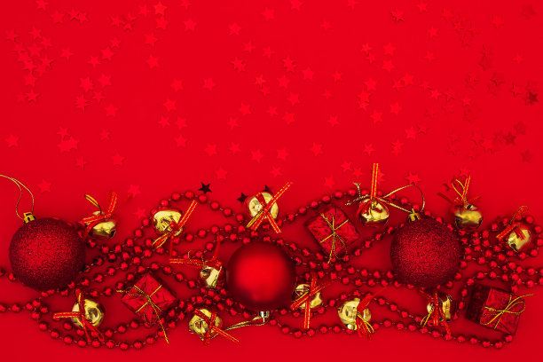 圣诞球，礼品盒，带蝴蝶结的金铃和红色背景上的红星珠花环。节日平铺圣诞卡和新年贺卡。图片下载