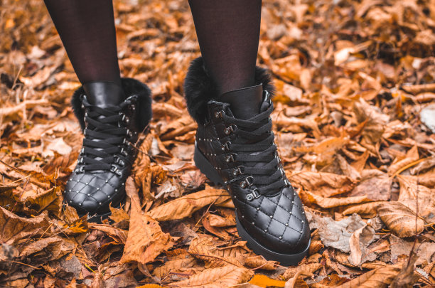 一个女孩穿着漂亮温暖的靴子站在秋天橙色的树叶，时尚的照片图片下载