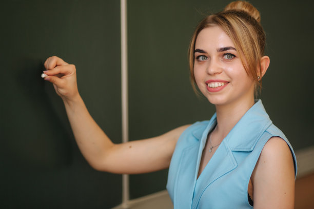 女老师在课桌上刷东西。年轻的老师图片下载