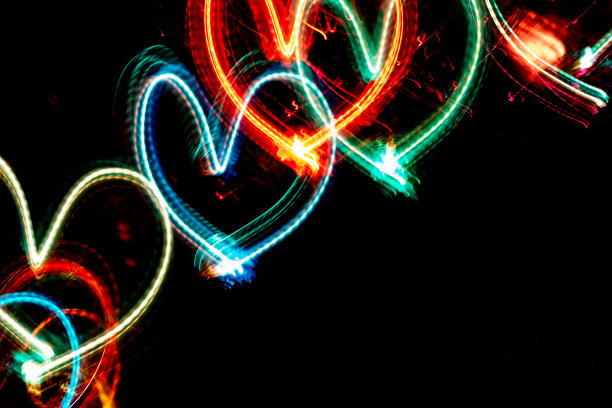 对角排的彩色霓虹灯发光的心在黑色的背景与复制空间。图片下载