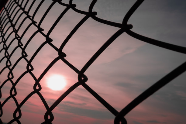 柔焦秋日日出的风景透过金属铁链围栏的背景纹理上方蓝色和粉色的天空，照片剪影的美丽图案为街头生活方式创意设计图片下载