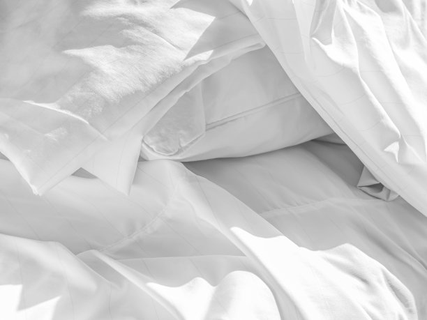 卧室枕头上的折叠拉链尘螨枕套和床上的褶皱白色床罩抽象黑白调。图片下载