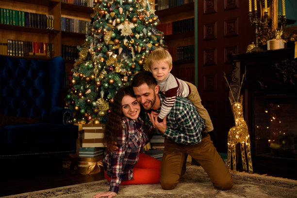 幸福的家庭，妈妈，爸爸和宝宝在家里的圣诞树上图片下载