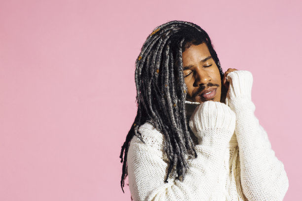 一个年轻人的肖像，闭着眼睛和温暖舒适的毛衣在工作室图片下载