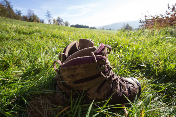 旅行。徒步旅行者在山上休息-靴子在草地上图片下载