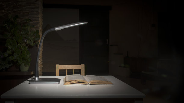 桌子上的台灯照亮了放在桌上的书。图片下载