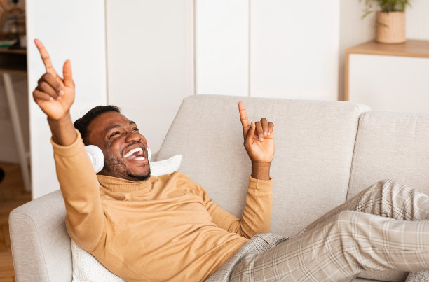 戴着耳机在家听音乐和唱歌的非洲人图片下载