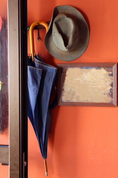 红墙上挂着一把伞和一顶旧帽子图片下载