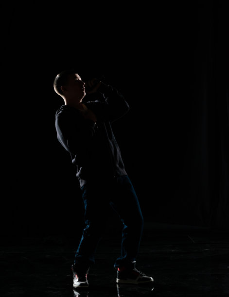 全长/一人/一人/正面的观点20-29岁的成年英俊的人高加索男性/年轻男子歌手/音乐家站/跳舞在黑人背景谁是唱歌/高兴和拿着麦克风图片下载