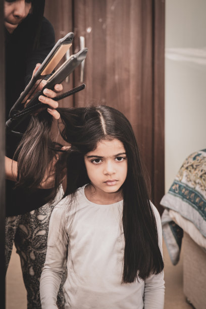6岁的小女孩在镜子前把头发拉直。图片下载