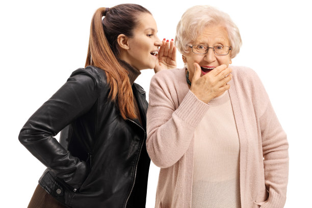 一个年轻女人在跟一个惊讶的年长女人耳语图片下载