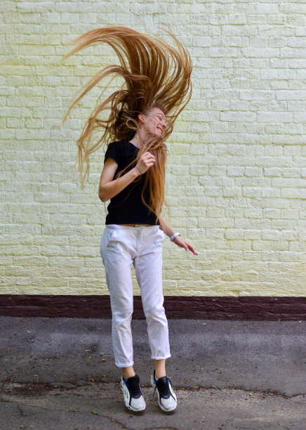 戴着耳机跳舞微笑的快乐年轻女人图片下载