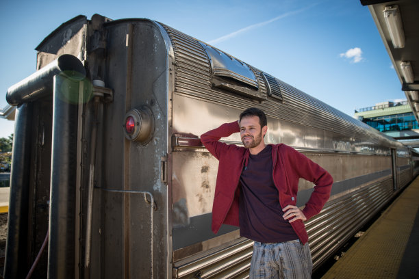 一个年轻人在火车旁微笑图片下载