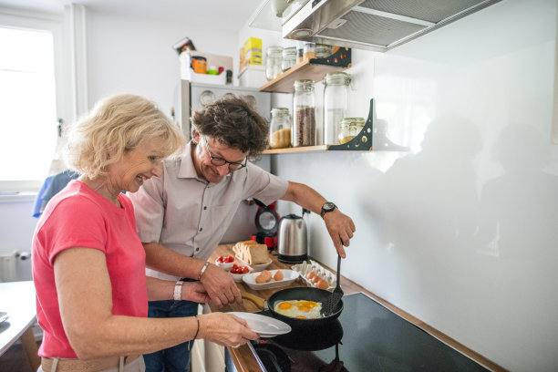 一对老年夫妇在厨房为早餐准备鸡蛋图片下载