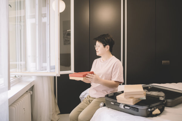 一位亚洲华裔女性在旅行前在房间里打包她的纪念品行李图片下载