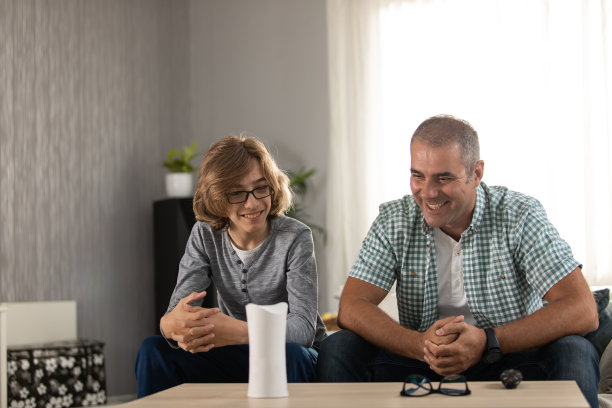 父亲和儿子在客厅使用虚拟助手图片下载