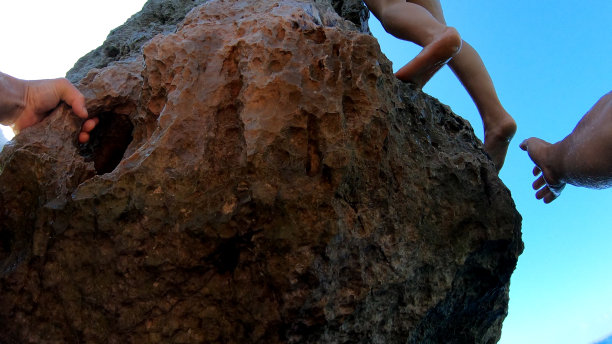 男人的手爬上海边的悬崖图片下载