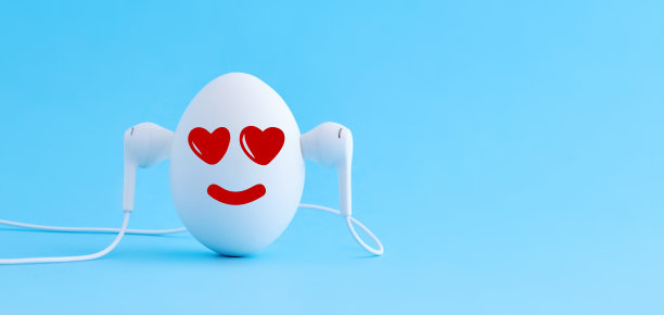 白色鸡蛋听浪漫的爱情音乐耳机在蓝色背景图片下载