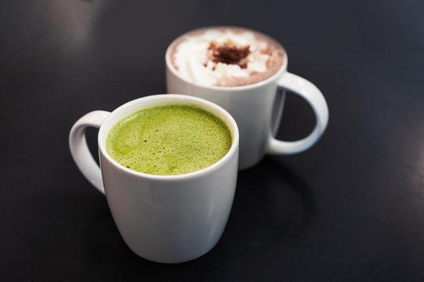 在一家时尚的咖啡馆里，你可以选择白色陶瓷杯里的日本抹茶绿茶，旁边是热巧克力图片下载
