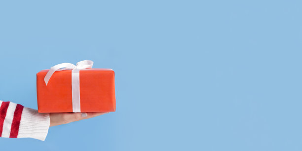 穿着条纹毛衣的女人拿着红色包装的礼物图片下载