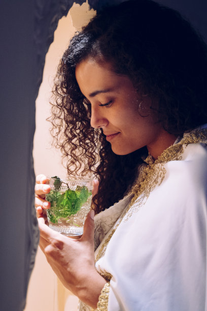 具有民族特征的阿拉伯年轻女子闻着阿拉伯薄荷茶。图片下载