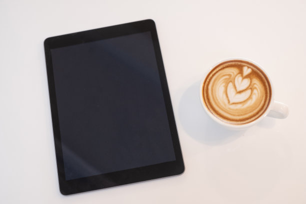 白色桌子上放着数码平板电脑和咖啡杯图片下载