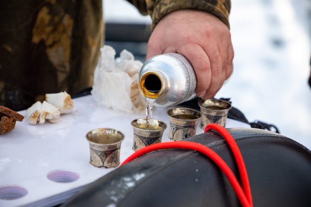 俄罗斯西伯利亚冬季捕鱼时，一名男子将伏特加倒向大自然图片下载